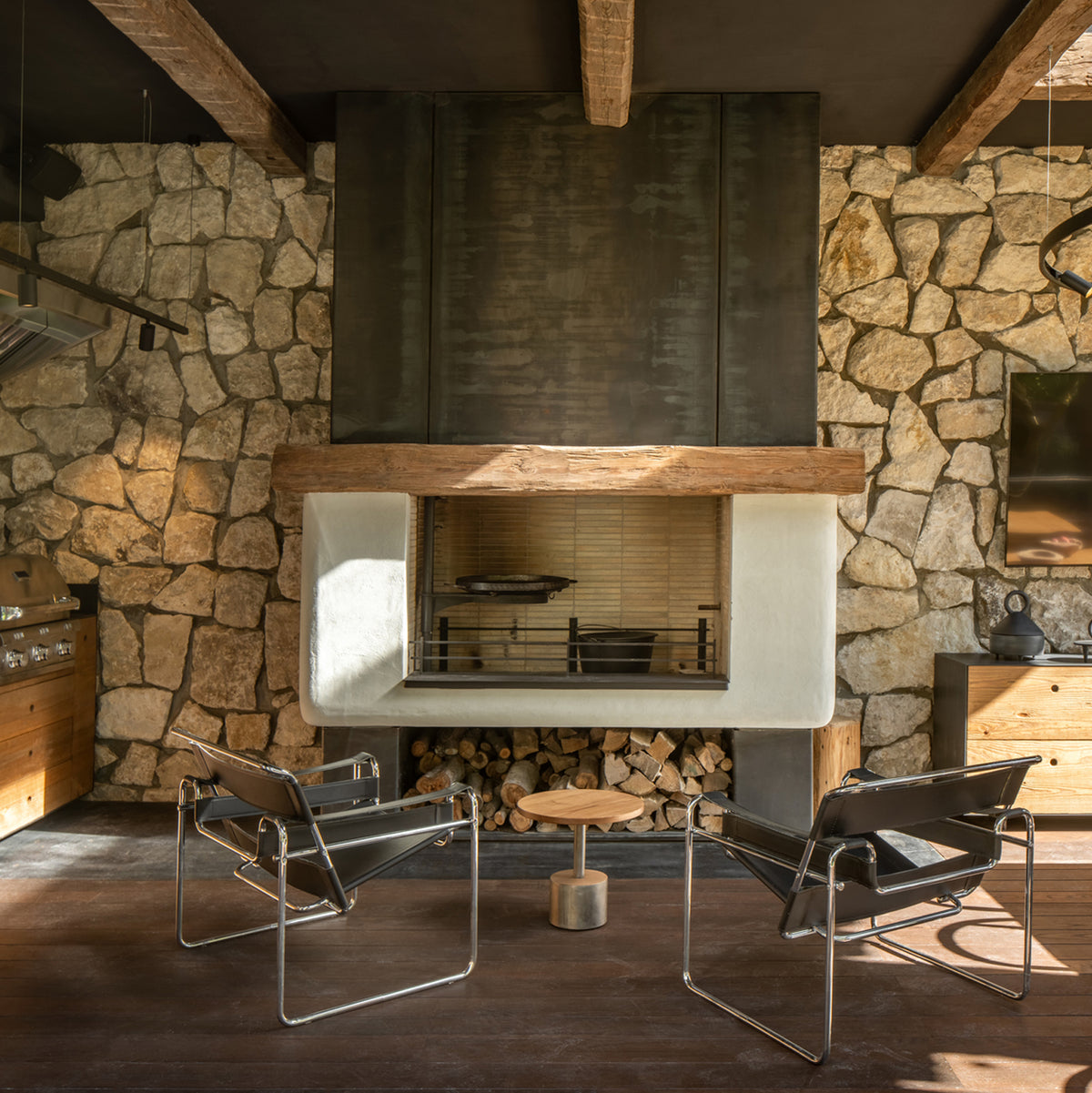 a living room with two chairs in front of a large stone fireplace