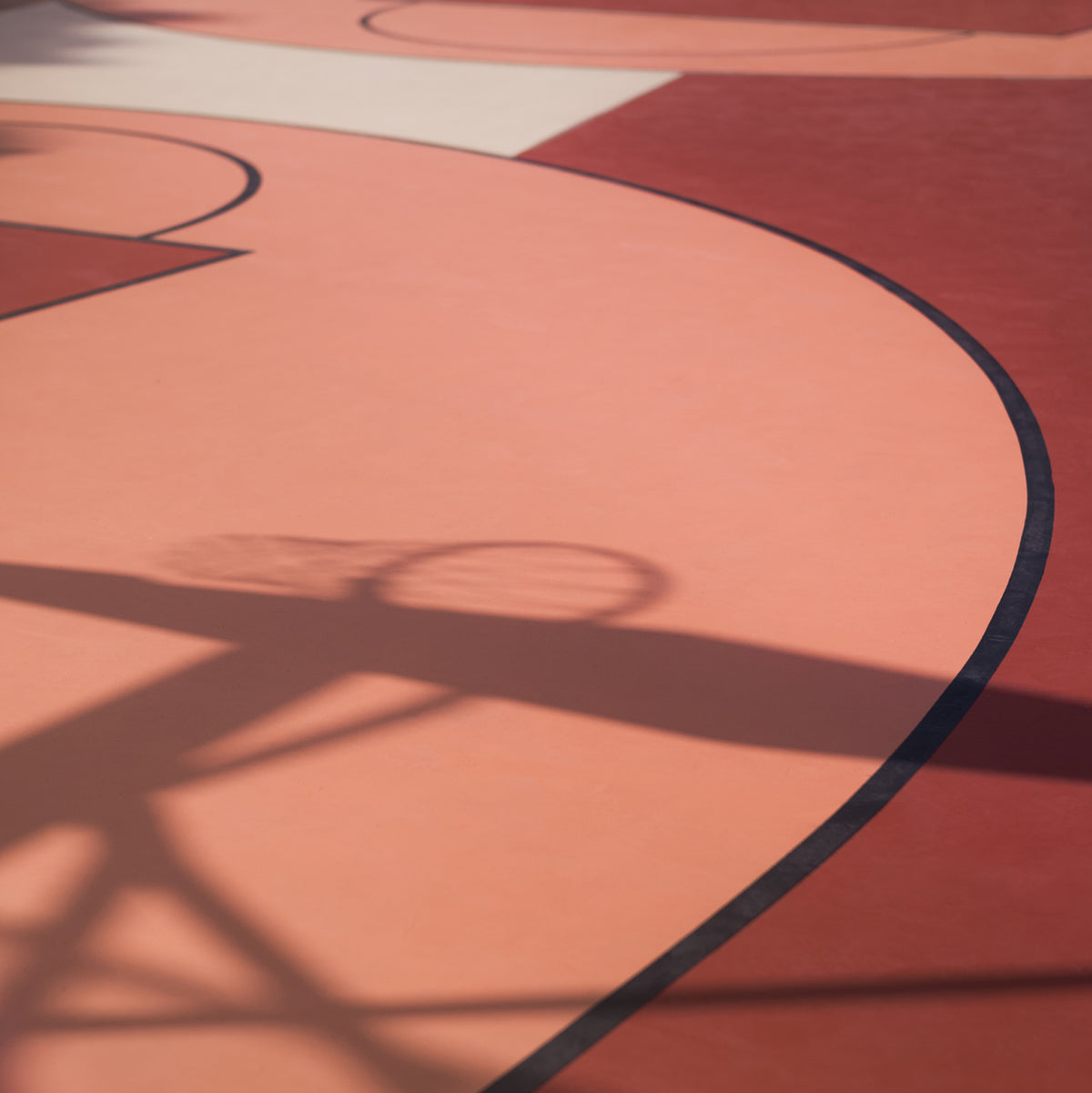 a red clay court with a shadow of a basketball net